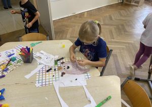 Zdjęcie przedstawia chłopca przyklejającego plaster misiowi.