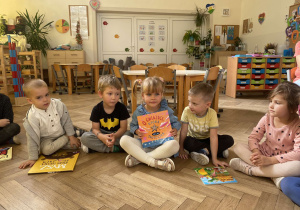 Zdjęcie przedstawia dzieci siedzące w kole i prezentujące swoje książki.