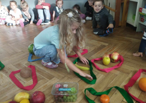 Na zdjęciu widzimy dziewczynkę, która umieszcza gruszkę w odpowiedniej pętli.