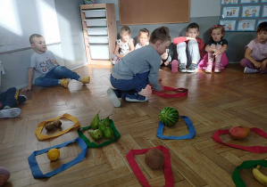 Na zdjęciu widzimy chłopca, który segreguje owoce do odpowiedniej pętli.