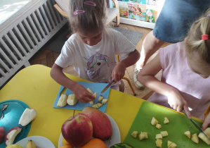 Na zdjęciu widzimy dziewczynki, które kroją owoce.