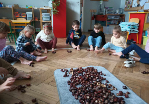 dzieci trzymają w palcach stóp kasztany