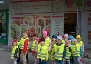 dzieci stoją przed wejsciem do sklepu osiedlowego