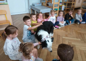 Pies wita się z dziećmi, podchodząc do nich