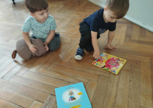Na zdjęciu widzimy dwóch chłopców. Jeden z nich decyduje którą książke weźmie na weekend do przeczytania w domu.