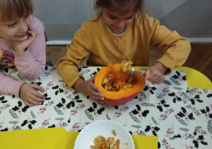 Na zdjęciu widzimy dziewczynkę, która wydrąża łyżką pestki z dyni.