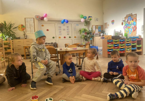 Zdjęcie przedstawia dzieci siedzące w kole i rozawiające ze sobą.