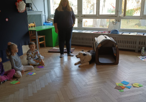 Pani stoi a obok leży pies.