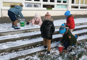 dzieci zbierają śnieg do wiaderek