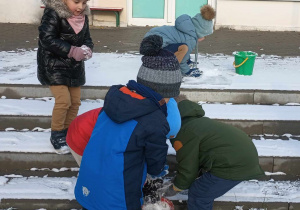 dzieci zbierają śnieg do wiaderek