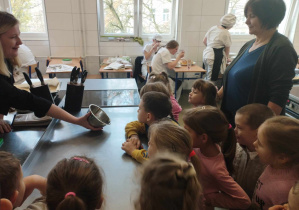 Na zdjęciu widzimy grupkę dzieci, które patrzą na miskę w której pocięta jest pietruszka.