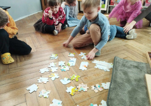 Na zdjęciu widzimy chłopca, który układa puzzle - mapa Świata.