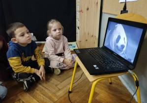 Na zdjęciu widzimy dwójkę dzieci, które oglądają film o zwierzętach zamieszkujących Azję.