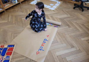 Na zdjęciu dziewczynka tworząca napis z ruchomego alfabetu