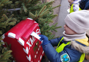 Na zdjęciu widzimy dziecko, które wkłada list do skrzynki. List ten będzie odczytany przez Mikołaja.