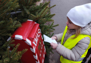 Na zdjęciu widzimy dziecko, które wkłada list do skrzynki. List ten będzie odczytany przez Mikołaja.