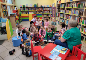 Zdjęcie przedstawia Panią Bibliotekarkę czytajacą dzieciom bajkę o tematyce świątecznej.