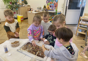 Zdjęcie przedstawia dzieci dekorujące posypkami czekoladę.