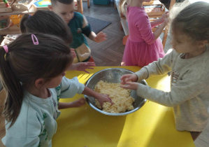 Na zdjęciu widzimy grupkę dzieci, które tworzą małe kuleczki.