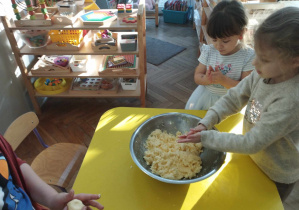 Na zdjęciu widzimy grupkę dzieci, które tworzą małe kuleczki.