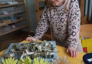dziewczynka przygląda się kwiatom i dinozaurom