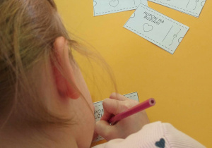 dziewczynka koloruje talony dla babci i dziadka