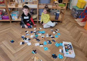 Dwoje małych dzieci, które zaczynają układać puzzle o tematyce kosmosu