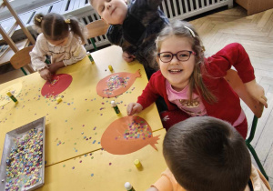 Dzieci wyklejają papierowy balon kolorowym konfetti