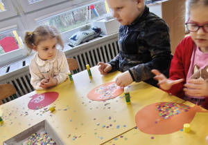 Dzieci wyklejają papierowy balon kolorowym konfetti