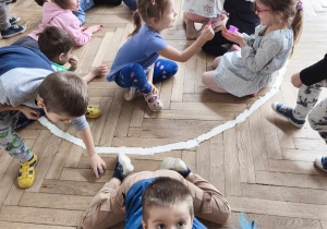 Dzieci wykoują doświadczenie z powietrzem i piórkiem