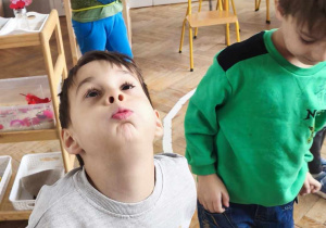 Dzieci wykonują doświadczenie z powietrzem i piórkiem