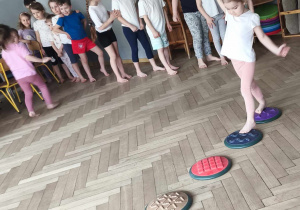 Dzieci ćwiczą na sali pokonują gimnastyczne kamienie