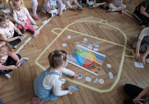 garnek wyklejony z taśmy, dziewczynka układa w nim zdjęcie przedstawiające zjawisko pogodwe