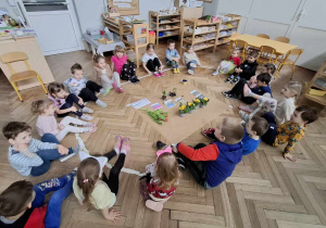na zdjęciu znajduje się grupa dzieic, przed nimi znajdują się rośliny