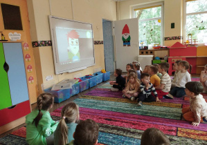 Na zdjęciu widzimy grupkę dzieci, które oglądają film na tablicy interaktywnej z serii sieciaki.pl.