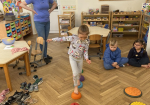 Zdjęcie przedstawia dziewczynkę idącą po ścieżce sensorycznej.
