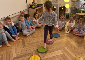 Zdjęcie przedstawia dziewczynkę idącą po ścieżce sensorycznej.