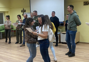 Zdjęcie przedstawia grupę rodziców podczas próby, wymieniających się spostrzeżeniami.