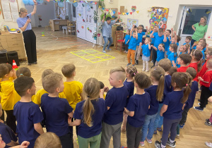 Zdjęcie przedstawia dzieci w kolorowych koszulkach, stojące w kole.