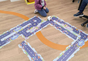 Zdjęcie przedstawia dziewczynkę poruszającą robotem przy pomocy pilota.