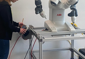 Zdjęcie przedstawia kobietę sterującą robotem.