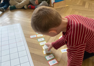 Zdjęcie przedstawia chłopca stawiającego robota na kolejnych kartach.