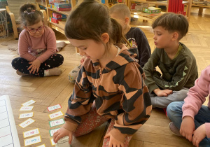 Zdjęcie przedstawia dziewczynkę stawiającą robota na kolejnych kartach.