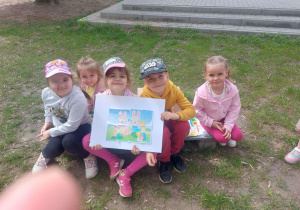 Zdjęcie przedstawia dzieci razem z fotografią królików.