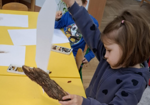dziewczynka trzyma kartkę papieru i korę drzewa