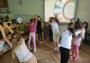 Zdjęcie przedstawia dzieci wykonujące ćwiczenia ruchowe z elementami jogi.