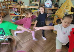 Zdjęcie przedstawia dzieci wykonujące ćwiczenia ruchowe z elementami jogi.