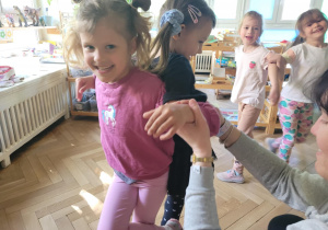 Zdjęcie przedstawia dzieci wykonujące ćwiczenia ruchowe z elementami jogi.