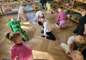 Zdjęcie przedstawia dzieci wykonujące ćwiczenia ruchowe z elementami jogi.