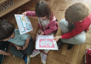 Na zdjęciu widzimy dzieci, które oglądają ilustracje przedstawiające godło Polski i obecną walutę - złotówkę.
